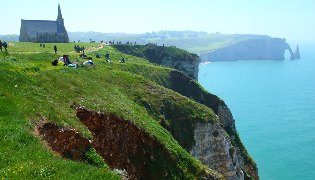 Étretat in der Normandie am Meer - Klippe La Falaise d'Amont mit Kapelle Notre-Dame-de-la-Garde, im Hintergrund Elefantenrüssel Porte d'Aval und Felsnadel Aiguille d'Étretat